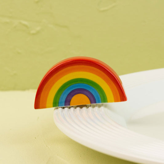 Colorful rainbow-shaped mini on a white plate against a light green background